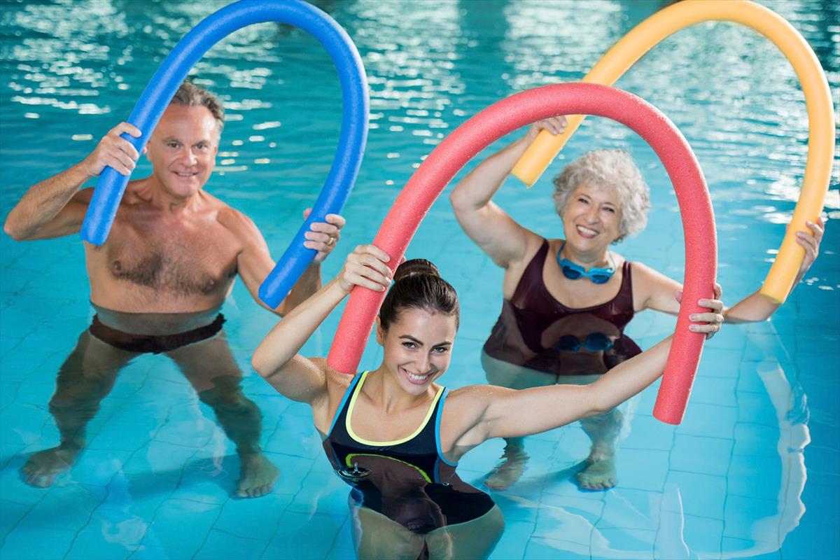 Gäste mit Poolnudeln bei der Wassergymnastik im Sportbecken